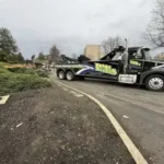 A black Bill's Towing heavy-duty wrecker truck driving on a road near Sutherlin, Oregon.