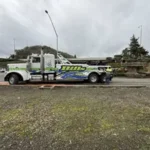 A white Bill's Towing heavy-duty wrecker truck parked near a highway overpass in Ashland, Oregon.