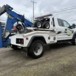 Rear view of a white Bill's Towing light-duty wrecker truck parked in a lot in Sutherlin, Oregon, showing the boom and wheel lift equipment.