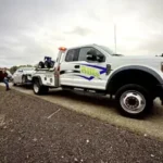 Bill's Towing white wrecker truck loading a disabled silver sedan on a highway roadside near Roseburg, Oregon.